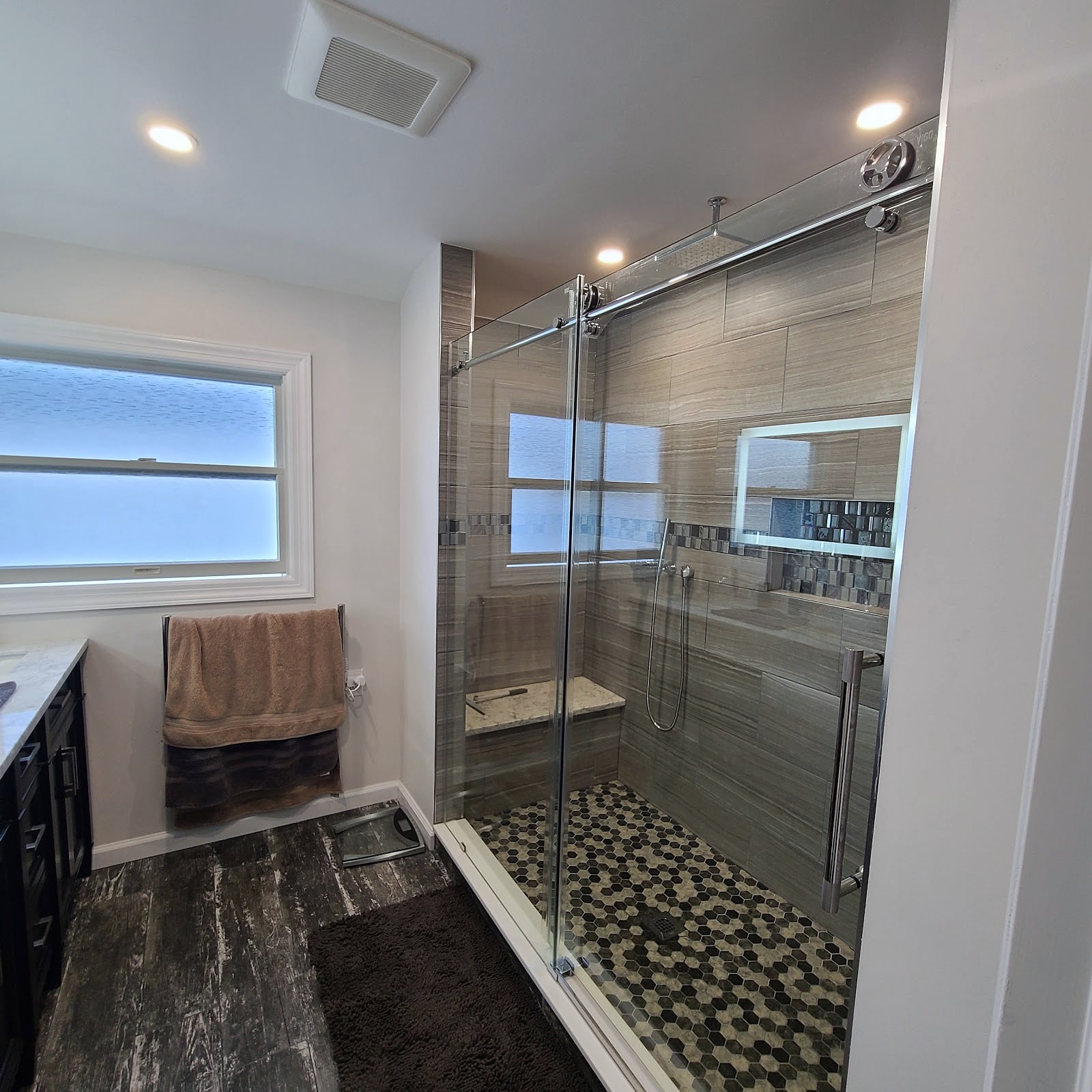 Remodeled bathroom with glass sliding shower door and hex tile floor