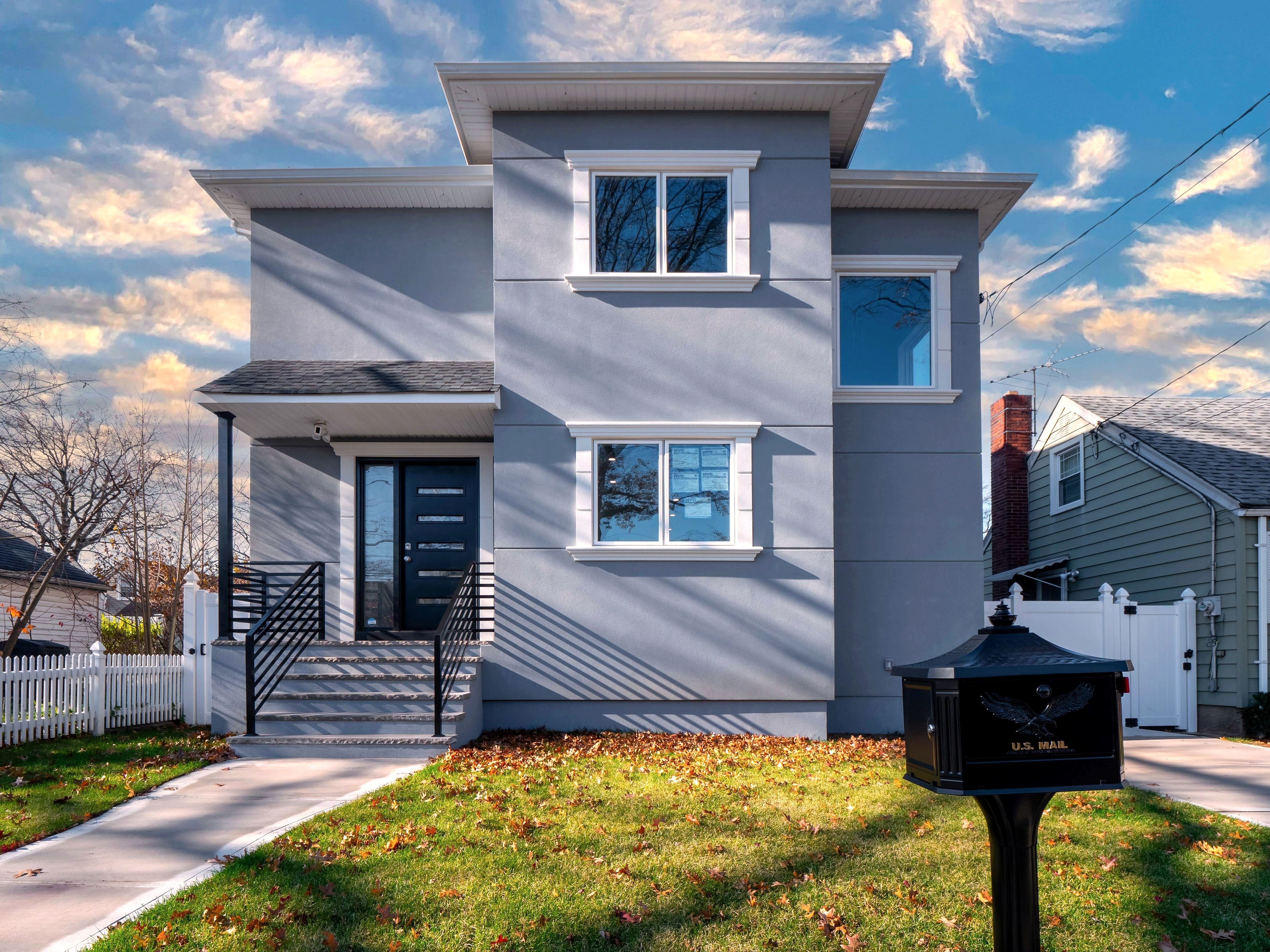 Gray stucco two-story house with black front door and railing